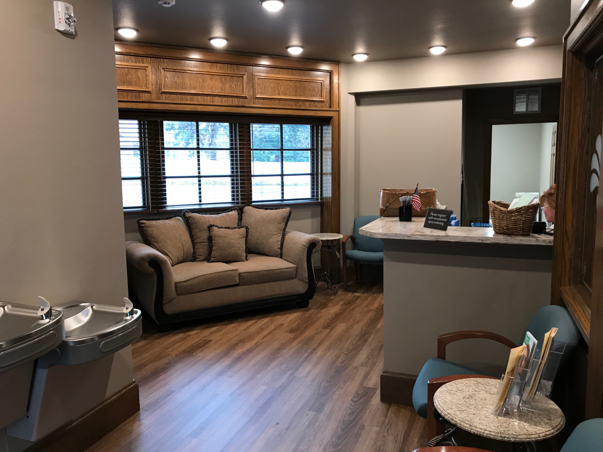 Reception and waiting area of the practice with a sofa, wood floors, and a registration desk